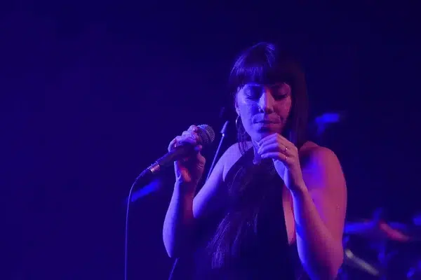 woman-on-stage-with-microphone-ina-blue-light-with-her-eyes-closed