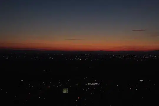 drone-shot-of-skyline-at-dramatic-sunset-over-the-very-darkened-cityscape