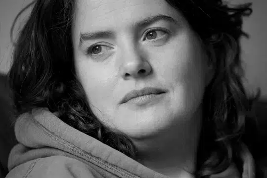 close-up-bw-photo-of-woman-looking-away-from-cameras-with-long-dark-hair-and-a-hoodie